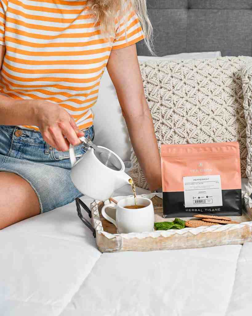 Female sitting on the bed pouring peppermint tea into a cup